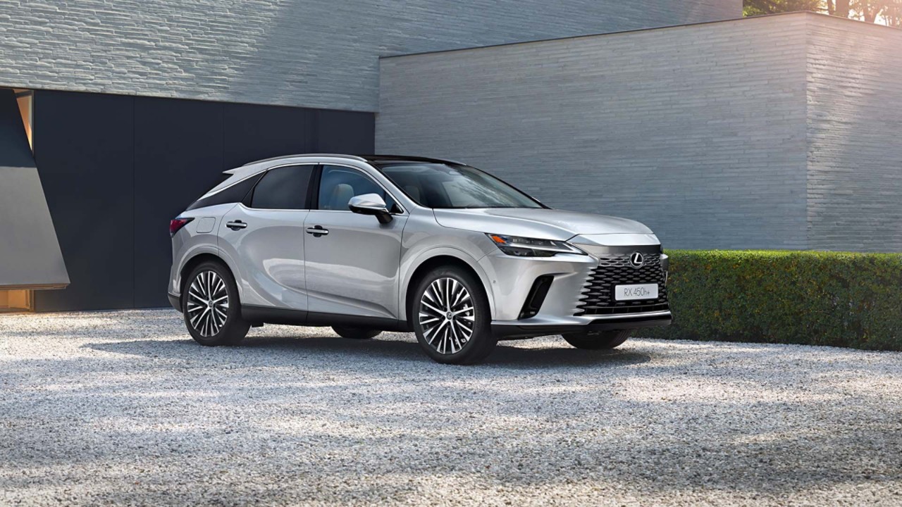Lexus Rx 450h+ je zaparkovaný na kamennej ceste pred veľkým domom