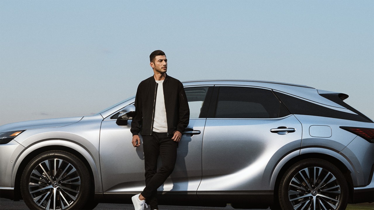 A man leaning against a parked Lexus RX