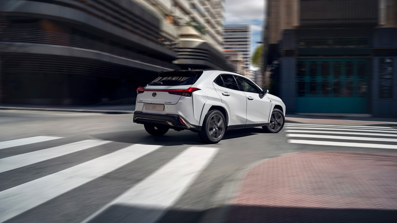 A Lexus UX driving round a corner in a town